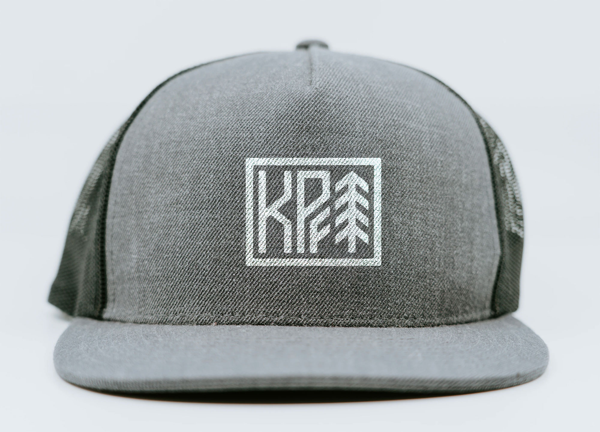 Gray trucker hat with the Kale Poland Fitness monogram embroidered in white on the crown